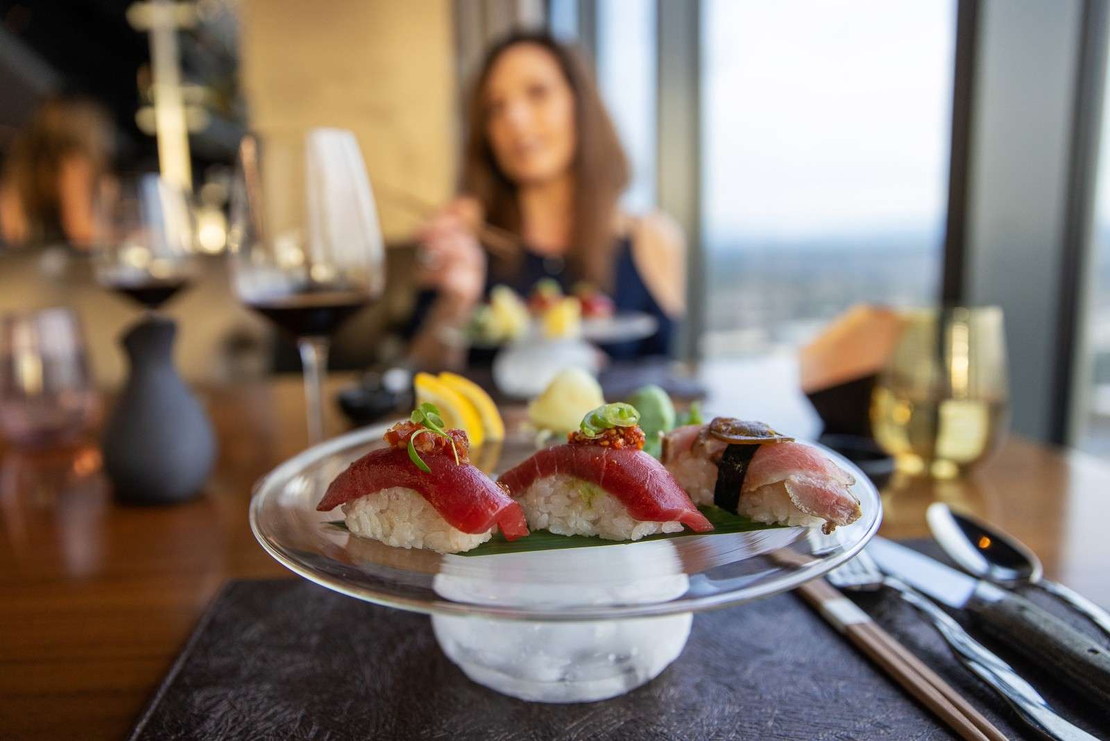 A woman sits across the table from another diner enjoying sushi